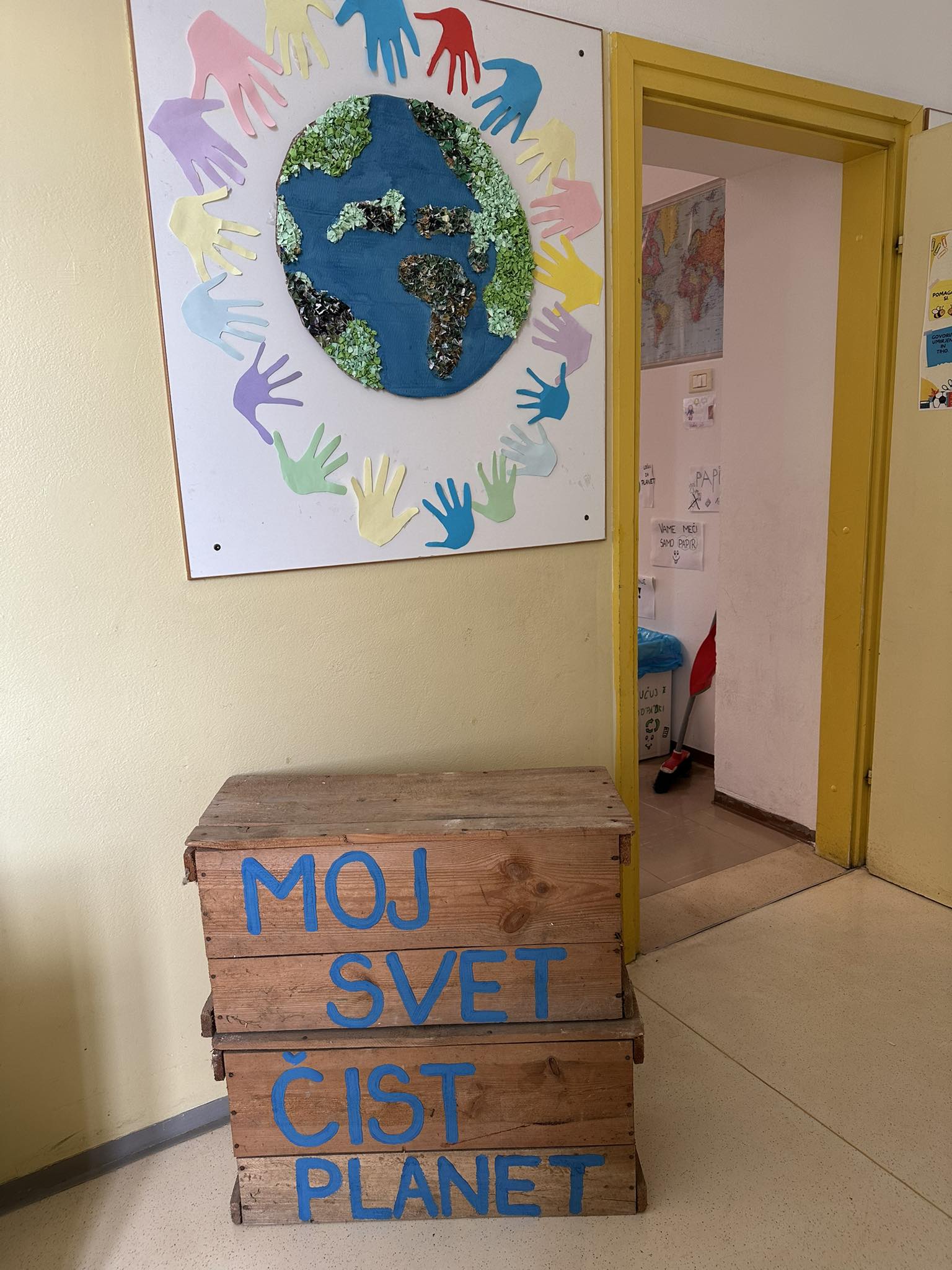 Okoljski plakat z Zemljo in lesen zaboj z napisom Moj svet, čist planet.